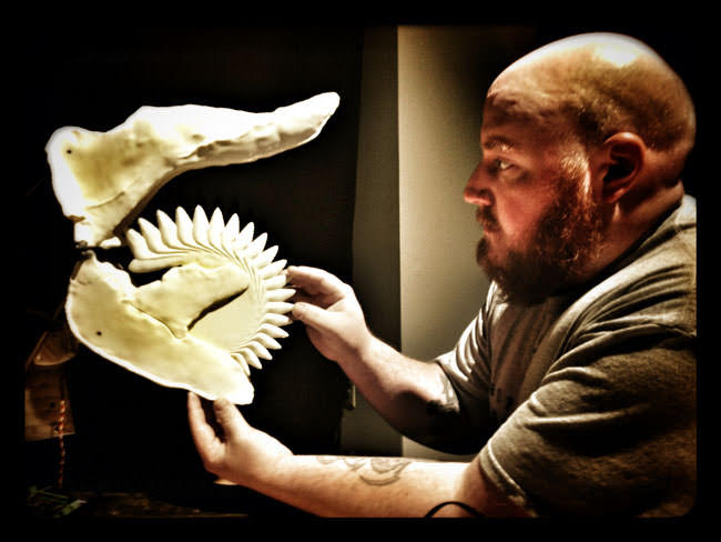 man holding fossil shark jaw reconstruction