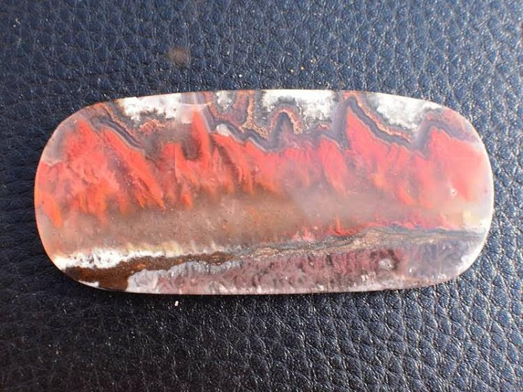 Flame Agate Cabochon with swirls of red and brown making abstract pattern on a long rounded-rectangle-shaped cabochon