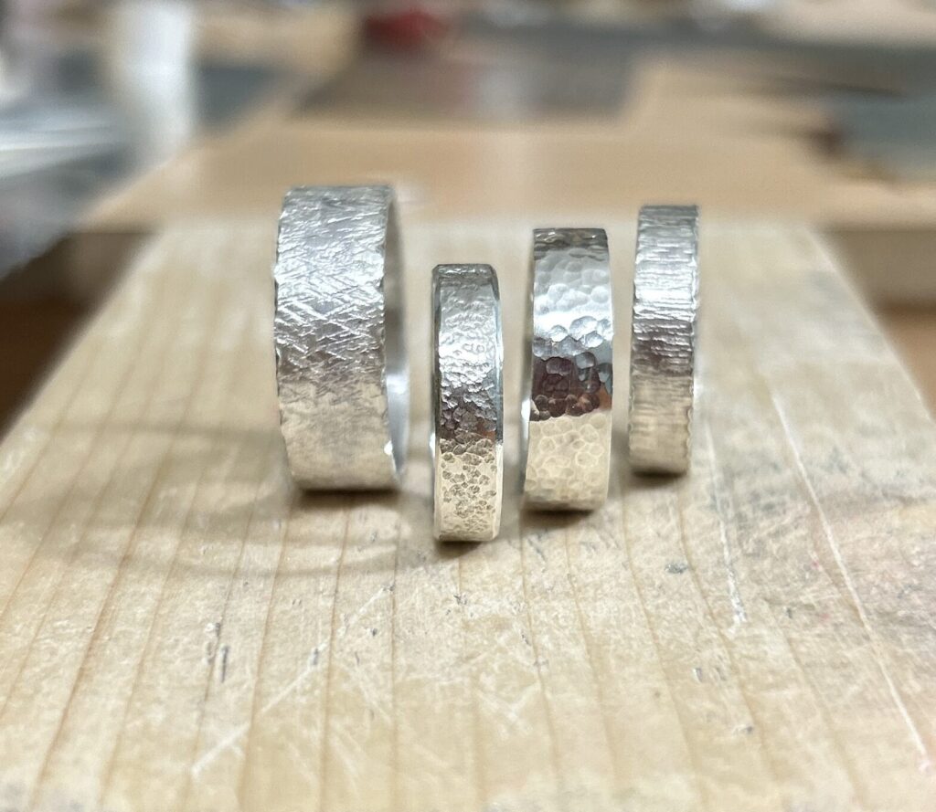 Four wide band silver rings with various textures