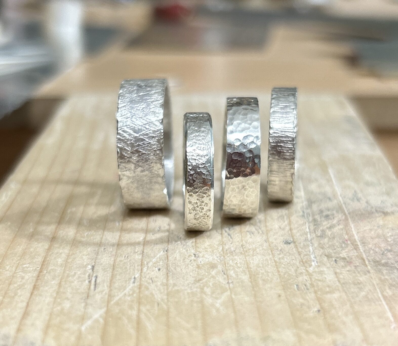 Four wide band silver rings with various textures